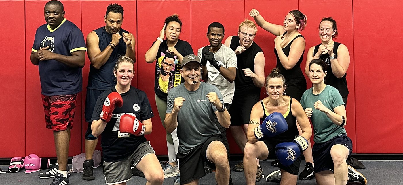 Fitness kickboxing class member punching a focus mitt at Baltimore Martial Arts Academy in Catonsville