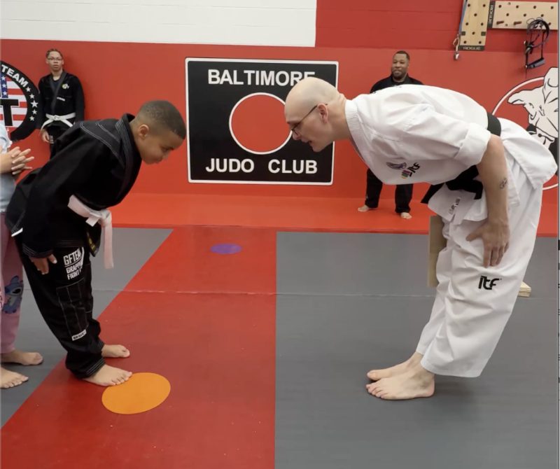 Davis Carlson bowing to a young student before a board break at Baltimore Martial Arts Academy